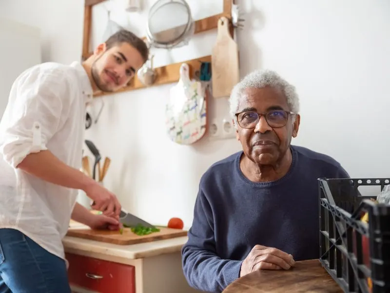 A home health aide prepares a meal alongside her senior client in his Las Vegas kitchen