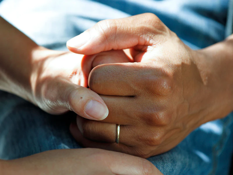 A nurse holds her chronic care patient's hands during a home visit