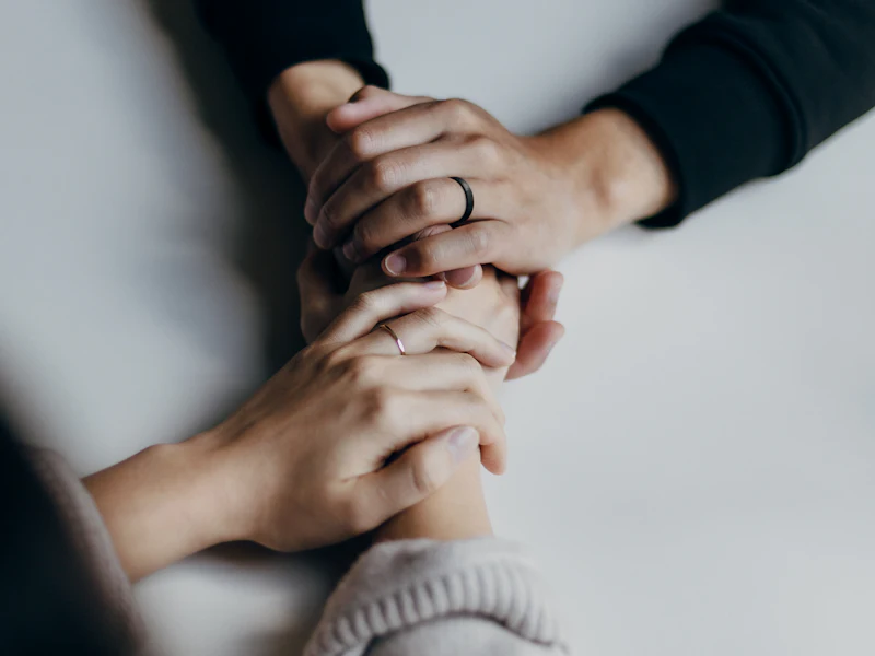 A caregiver gently holds an elderly woman's hands in comfort
