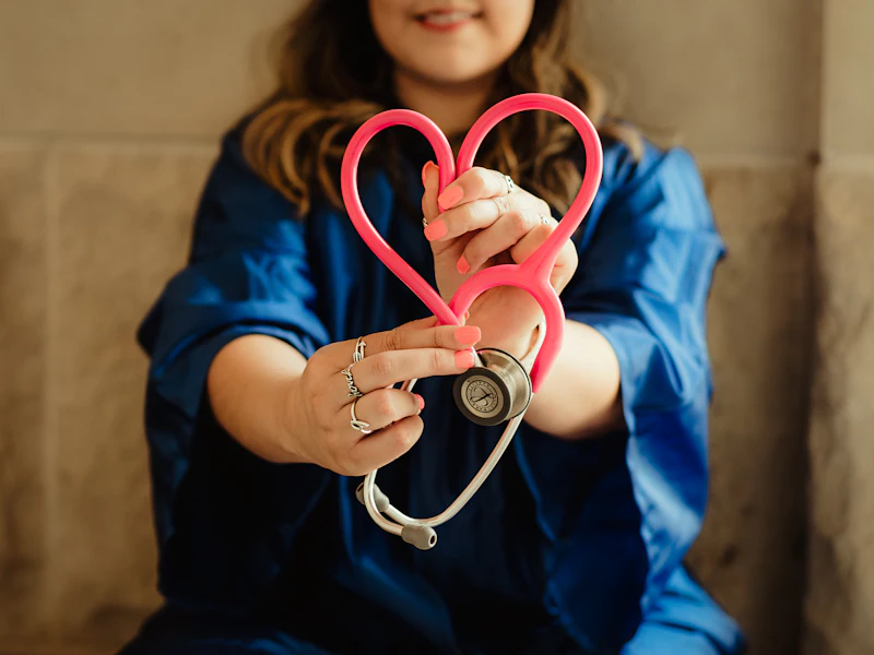 A nurse holds a stethoscope shaped into a heart